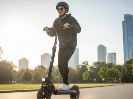 Young rider commuting on black CEMOTO electric scooter in city park with skyline background